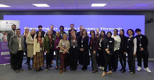 HRUC staff from our Apprenticeships and Skills team. They are standing in front of a purple screen with a banner to the left side.