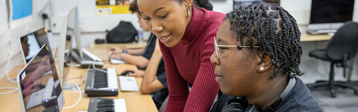 Hayes Music student working at the computer with the help of a teacher